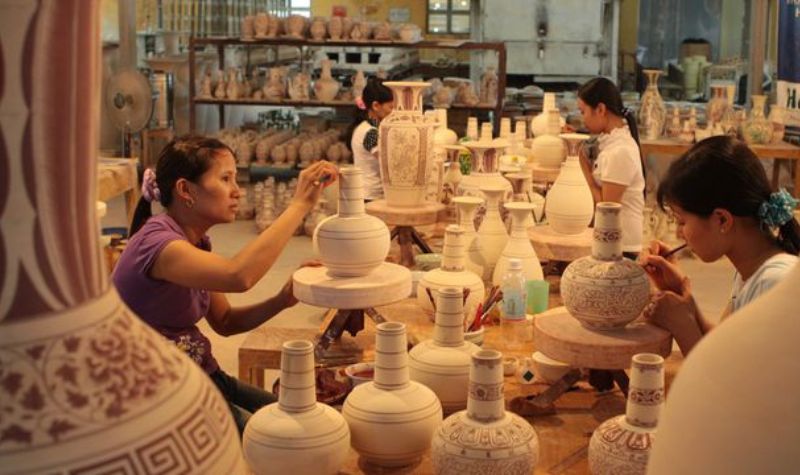 Thợ gốm đang vẽ họa tiết lên các bình gốm